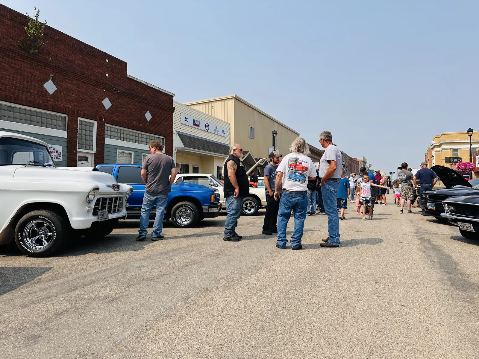 Main Street Carrington lined with classic trucks and cars with crowds walking between them at the OK Tire Round Up