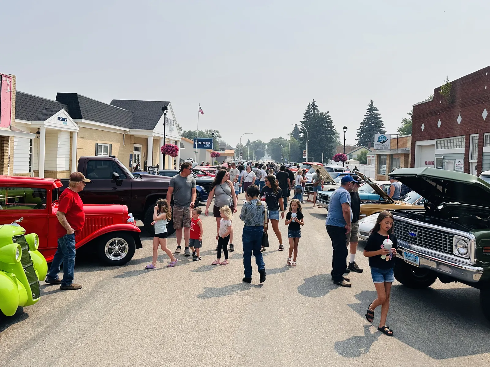 Large crowd and kids walking down Main Street Carrington between classic trucks and cars