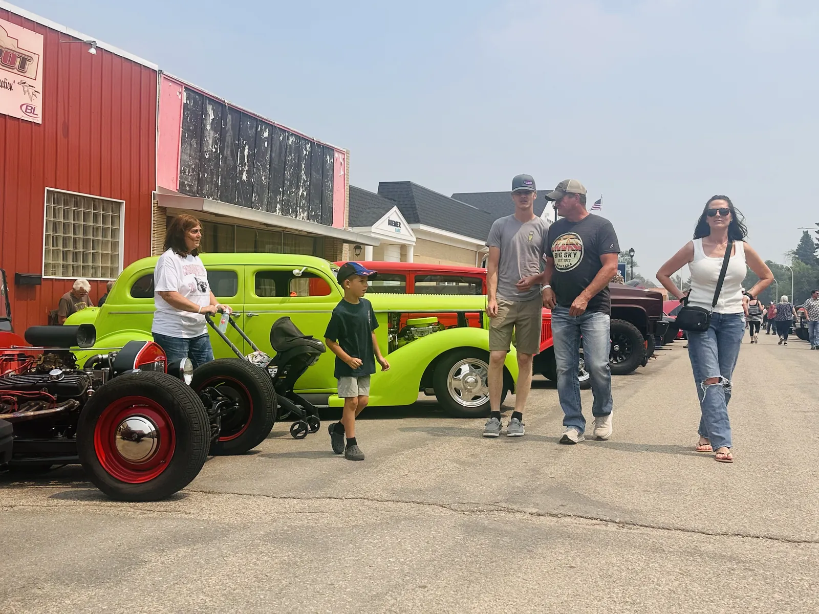 Lime green classic hot rod on Main Street with a family walking past