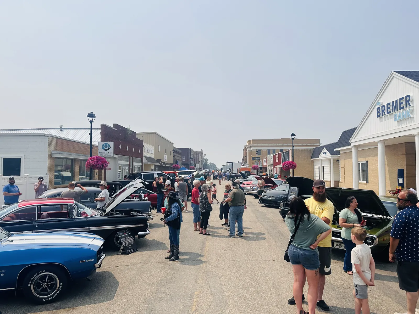 Wide view of Main Street Carrington packed with classic cars, spectators, and the Bremer Bank building